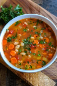 A bowl of Million Dollar Soup garnished with fresh herbs and vegetables.