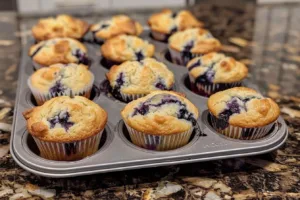 Freshly baked lemon blueberry muffins with a golden crust and juicy blueberries.