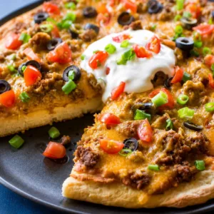 Delicious Taco Pizza topped with beans, salsa, beef, cheese, and fresh toppings.